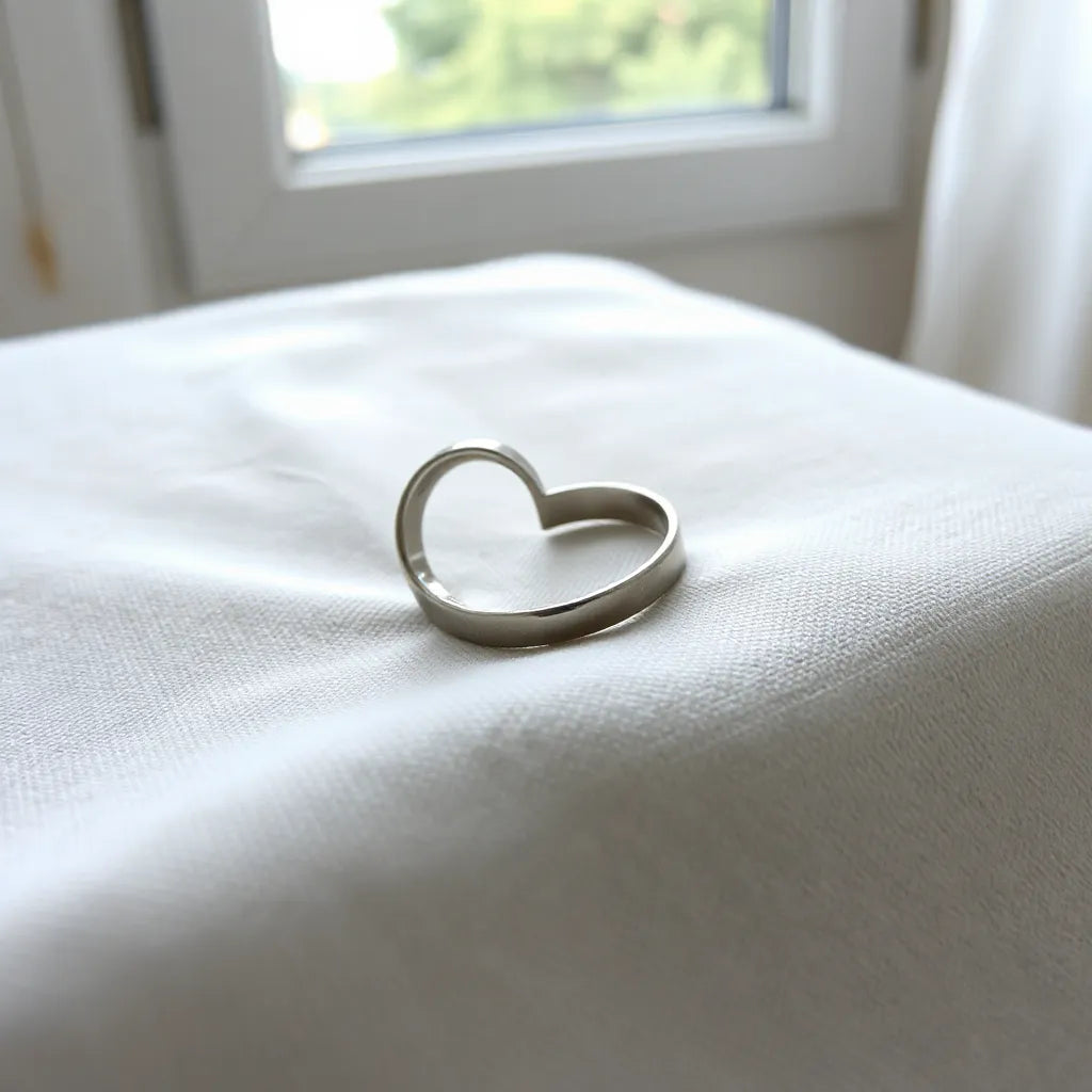 Stainless steel heart-shaped ring on light fabric with soft natural lighting